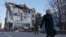 A woman walks past an office building damaged by shelling in Donetsk, Russian-controlled Ukraine, Dec. 15, 2022. 