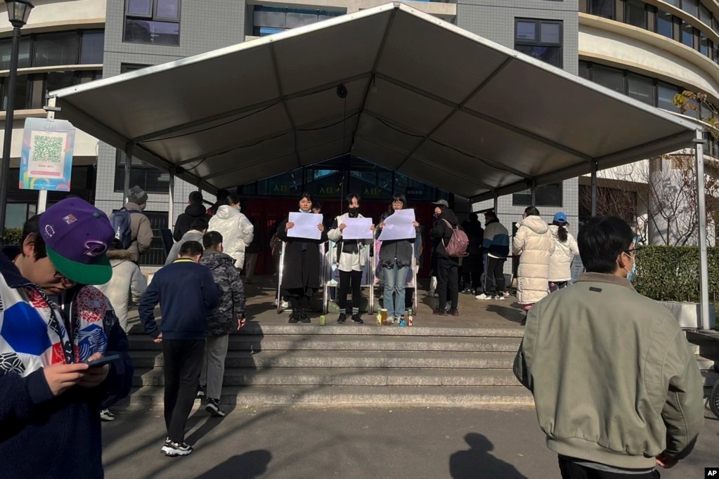 北京清华大学的学生手举白纸抗议严厉的防疫政策，悼念日前在新疆乌鲁木齐市死于火灾的至少10名遇难者。 （2022年11月27日）(photo:VOA)