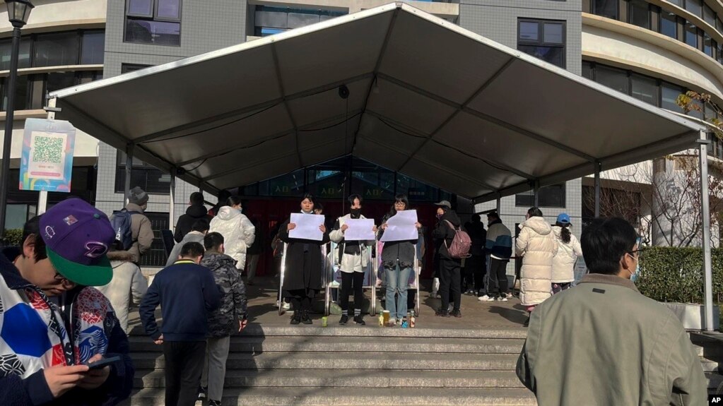 北京清华大学的学生手举白纸抗议严厉的防疫政策，悼念日前在新疆乌鲁木齐市死于火灾的至少10名遇难者 (022年11月27日)(photo:VOA)