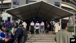 北京清華大學的學生手舉白紙抗議嚴厲的防疫政策，悼念日前在新疆烏魯木齊市死於火災的至少10名遇難者。 （2022年11月27日）