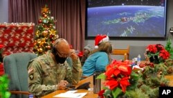 FILE - In this photo released by the US Department of Defense, volunteers answer phones and emails from children around the globe during annual NORAD Tracks Santa event at Peterson Air Force Base in Colorado Springs, Colo., on Dec. 24, 2021.