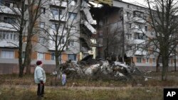 Una mujer pasa frente a un edificio de apartamentos dañado por los bombardeos rusos en Bakhmut, el lugar de las batallas más duras con las tropas rusas, en la región de Donetsk, Ucrania, el 11 de diciembre de 2022.