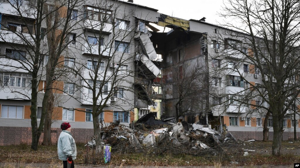2022 年 12 月 11 日，在乌克兰顿涅茨克地区，一名妇女走过一栋被俄罗斯炮击损坏的公寓楼，巴赫穆特是与俄罗斯军队发生最激烈战斗的地点。(photo:VOA)