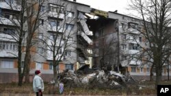 2022 年 12 月 11 日，在烏克蘭頓涅茨克地區，一名婦女走過一棟被俄羅斯砲擊損壞的公寓樓，巴赫穆特是與俄羅斯軍隊發生最激烈戰鬥的地點。