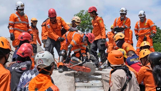 Los rescatistas usan una sierra mientras intentan recuperar el cuerpo de una víctima del terremoto de debajo de los escombros de un edificio derrumbado en Cianjur, Java Occidental, Indonesia, el 22 de noviembre de 2022.