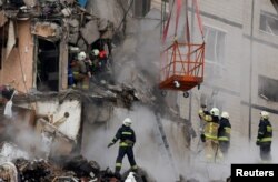 Emergency personnel evacuate an injured woman at the site where an apartment block was heavily damaged by a Russian missile strike in Dnipro, Ukraine, Jan. 15, 2023.