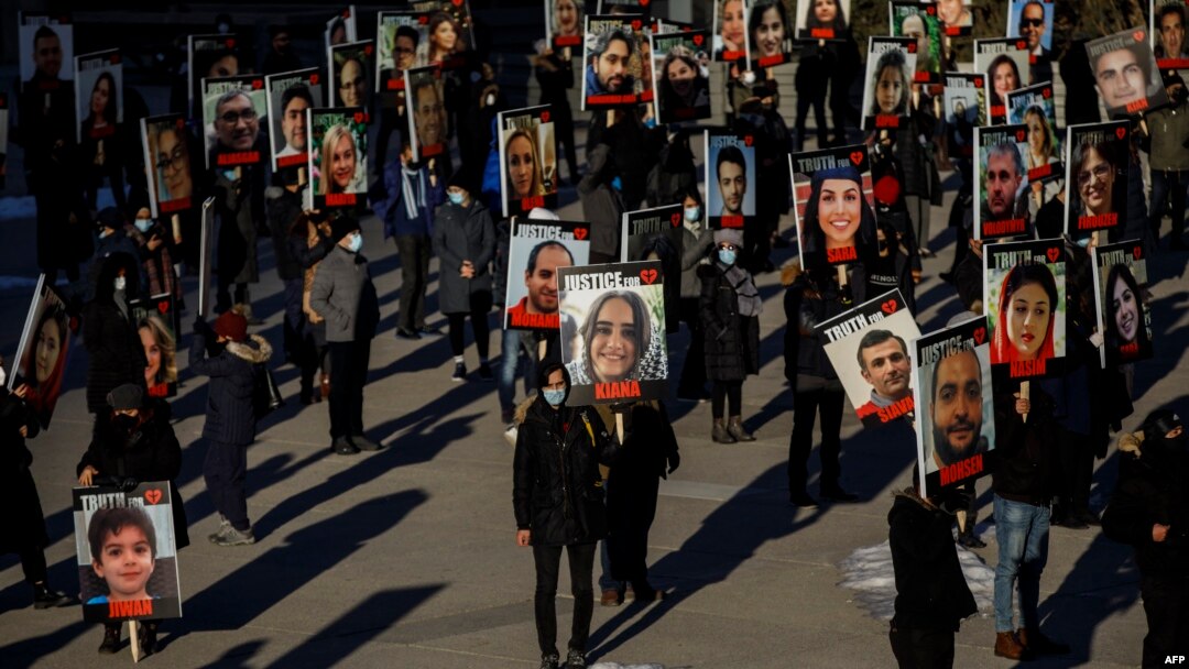 FILE - People hold signs with images of the victims of the downed Ukraine International Airlines Flight PS752, Jan. 8, 2021, in Toronto.