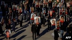 FILE - People hold signs with images of the victims of the downed Ukraine International Airlines Flight PS752, Jan. 8, 2021, in Toronto.