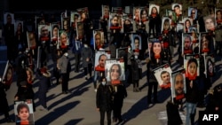 FILE - In this photo taken Jan. 8, 2021, people hold signs with images of the victims of the downed Ukraine International Airlines Flight PS752.