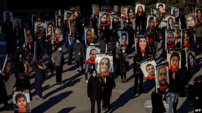 FILE - In this file photo taken on January 8, 2021, People hold signs with images of the victims of the downed Ukraine International Airlines flight PS752.