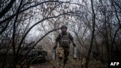 A Ukrainian artilleryman from the 24th brigade carries empty artillery cartridge cases at a position along the front line in the vicinity of Bakhmut, Donetsk region on Dec. 10, 2022. 
