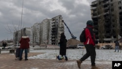 Residents watch as a bombed building is dismantled in Borodyanka, Kyiv region, Ukraine, Dec. 13, 2022.