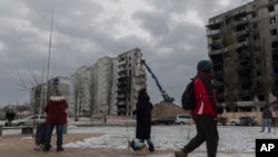 Residents watch as a bombed building is dismantled in Borodyanka, Kyiv region, Ukraine, Dec. 13, 2022.
