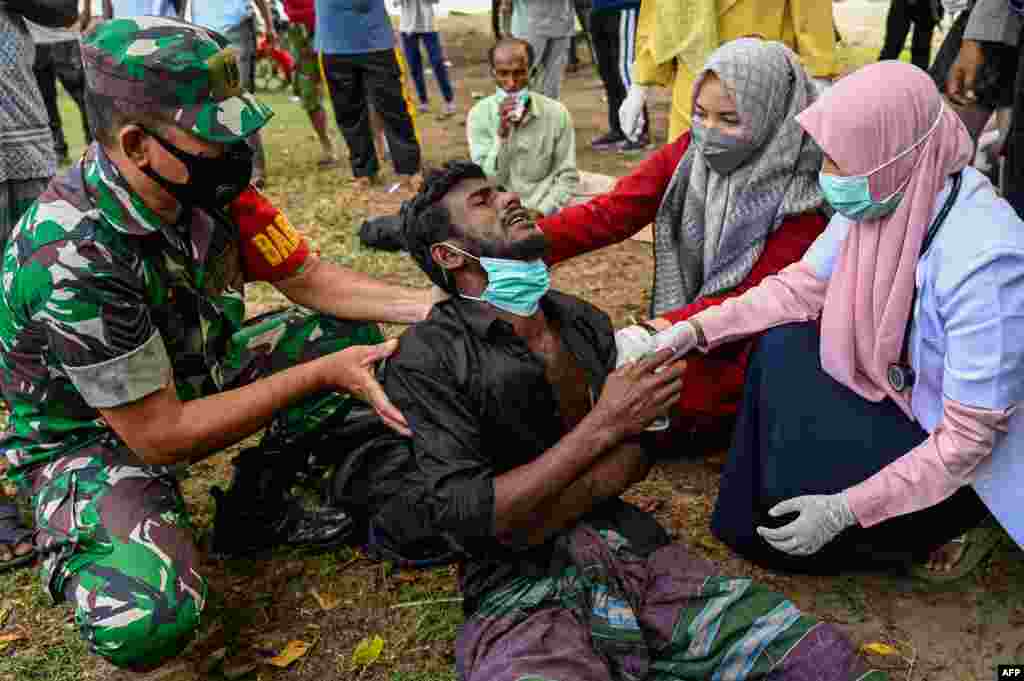 Health workers check a Rohingya refugee who was feeling sick after his arrival by boat in Krueng Raya, Indonesia&#39;s Aceh province.