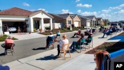 Neighbors of Lisa and Larry Neula watching them perform a Hawaiian dance in their driveway in Sacramento, Calif., in March 2022. The two began their driveway performances during lockdown and have kept them up. (John Pasamonte via AP)