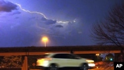 Un vehículo circula a lo largo de una calle de Jackson, Mississippi, EEUU, mientras los relámpagos atraviesan el cielo, el martes 29 de noviembre de 2022 por la noche.