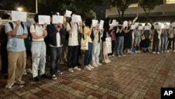 Protesters hold up blank white papers during a commemoration for victims of a recent Urumqi deadly fire at the Chinese University of Hong Kong in Hong Kong, Nov. 28, 2022.