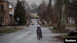 Una residente camina por una calle vacía mientras continúa el ataque de Rusia contra Ucrania, en Bakhmut, Ucrania. El presidente Volodymyr Zelenskyy visita este martes la zona.