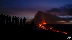 People watch and record images of lava from the Mauna Loa volcano, Dec. 1, 2022, near Hilo, Hawaii.