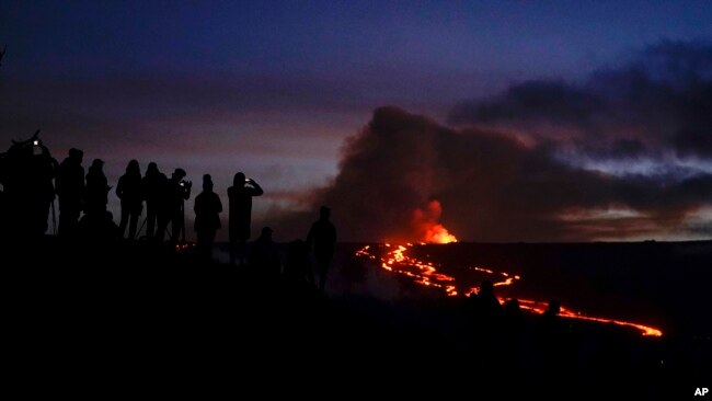 People watch and record images of lava from the Mauna Loa volcano, Dec. 1, 2022, near Hilo, Hawaii.