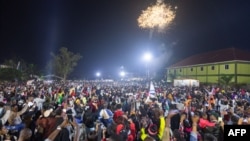 Fireworks light up the sky as people react while they celebrate after counting down to the new year at Miracle Center Cathedral in Kampala, Uganda, Jan. 1, 2023. 