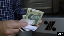 FILE - A man withdraws Iranian Rial notes from an automated teller machine in the capital Tehran on July 31, 2018. 