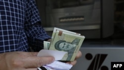 FILE - A man withdraws Iranian rial notes from an ATM in Tehran, Iran, on July 31, 2018. The rial has lost 29% of its value since nationwide protests started after the death in police custody of a 22-year-old Kurdish Iranian woman on Sept. 16, 2022.