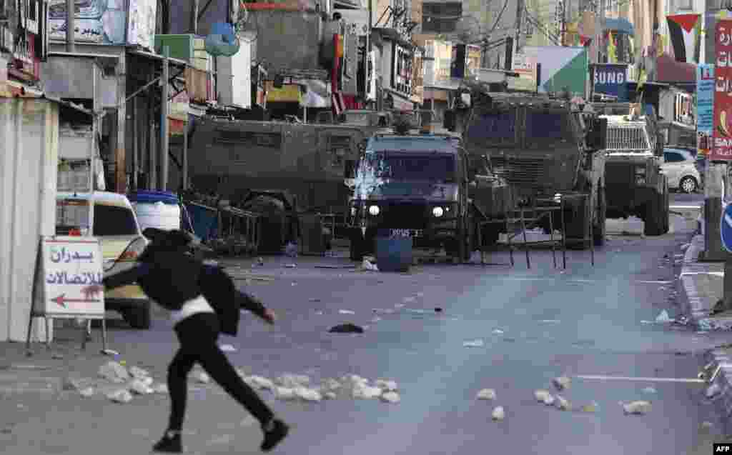 Palestinian protesters hurl rocks at the Israeli army during a reported raid in the Palestinian Askar refugee camp near Nablus in the occupied West Bank.