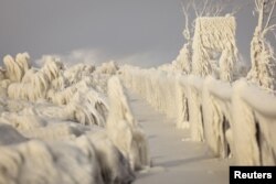 Es yang terbentuk akibat semburan ombak dari Danau Erie menutupi jembatan penyeberangan selama badai musim dingin di Irving, New York, Amerika Serikat, 24 Desember 2022. (REUTERS/Lindsey DeDario)