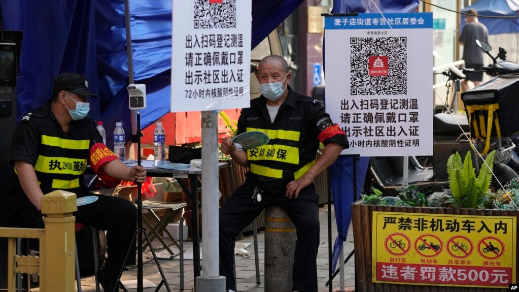 两名执勤保安在北京一个居民小区外检查居民需要出入小区的健康码。（2022年11月9日）