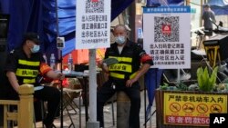 两名执勤保安在北京一个居民小区外检查居民需要出入小区的健康码。（2022年11月9日）