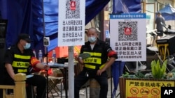 资料照：两名执勤保安在北京一个居民小区外检查居民需要出入小区的健康码。（2022年11月9日）