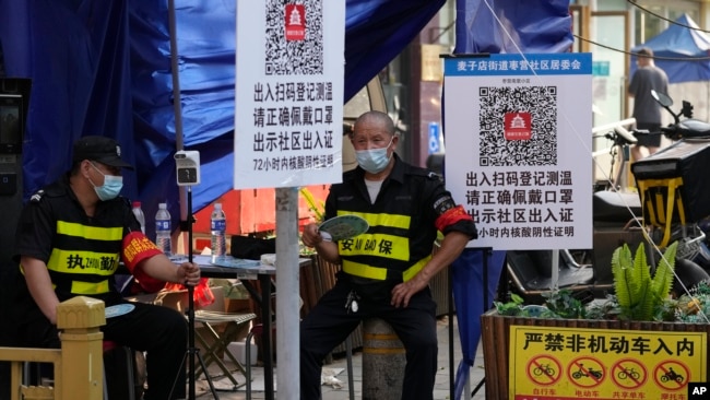 资料照：两名执勤保安在北京一个居民小区外检查居民需要出入小区的健康码。（2022年11月9日）