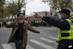 FILE - A protester holding flowers is confronted by a police officer during a protest on a street in Shanghai, China November 27, 2022. (AP Photo)
