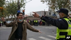 A protester holding flowers is confronted by a policeman during a protest on a street in Shanghai, China, Nov. 27, 2022. Authorities eased anti-virus rules in scattered areas but affirmed China's severe "zero-COVID" strategy Monday.