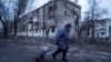 A local woman walks to the distribution point of humanitarian aid in front of housing which was damaged by Russian shelling in Kupiansk, Kharkiv region, Ukraine, Dec. 28, 2022. 