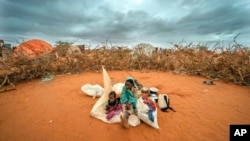 FILE - A Somali woman and child wait to be given a spot to settle at a camp for displaced people amid a drought on the outskirts of Dollow, Somalia on Sept. 20, 2022. 