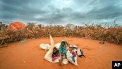 FILE - A Somali woman and child wait to be given a spot to settle at a camp for displaced people amid a drought on the outskirts of Dollow, Somalia on Sept. 20, 2022. 