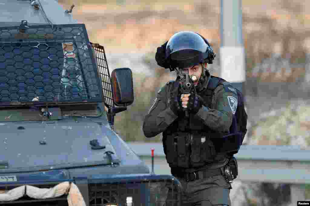 Припадник на израелската гранична полиција го вперува оружјето за време на судирот со Палестинците кај Беит Ел, во близина на Рамала, на Западниот Брег окупиран од Израел.