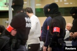 Polisi khusus berdiri di belakang terdakwa dalam kotak kaca yang dirancang khusus saat dimulainya persidangan serangan Brussel 22 Maret 2016, di gedung Justitia di Brussel, Senin, 5 Desember 2022. (Olivier Matthys/Pool via REUTERS)