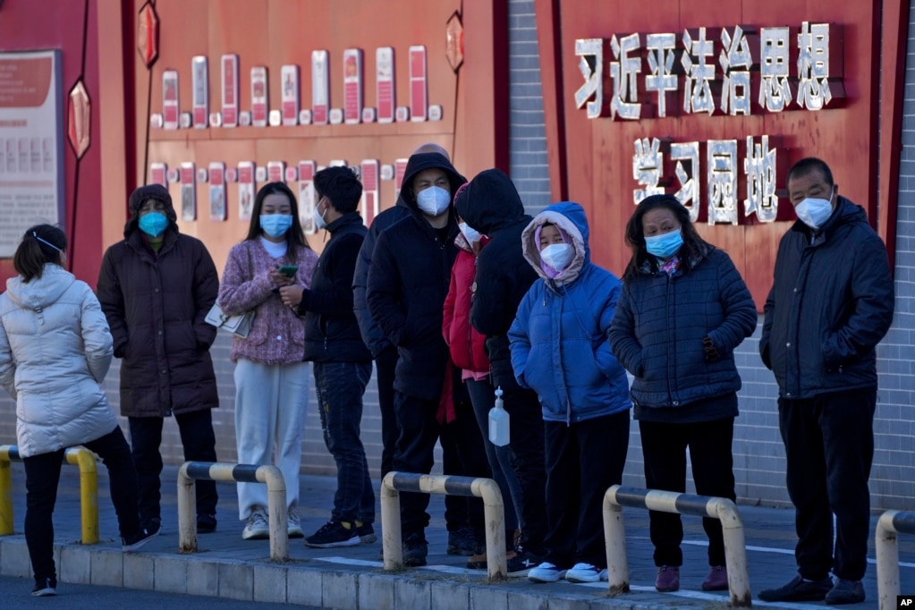 北京市民在宣传习近平思想的标语墙前排队等候接受核酸检测。（2022年12月5日）(photo:VOA)