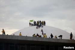 Los partidarios del expresidente de Brasil, Jair Bolsonaro, en la parte superior de la cúpula del Congreso Nacional durante una manifestación contra el presidente Luiz Inácio Lula da Silva, en Brasilia, Brasil, el 8 de enero de 2023.