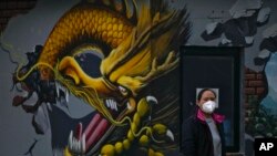 2022年11月23日，一女子在北京戴口罩在在一壁画前