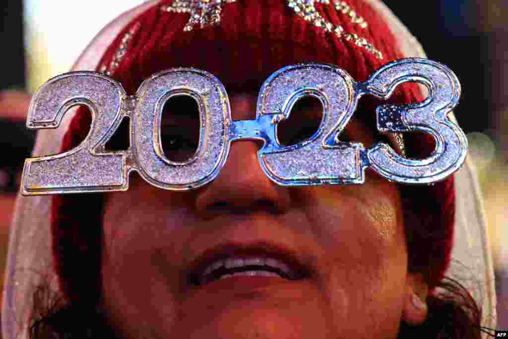 Una persona usa anteojos 2023 mientras espera la llegada del Año Nuevo, en Times Square, Nueva York, el 31 de diciembre de 2022. [AFP]