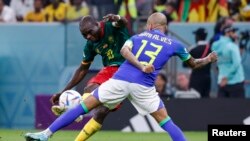 El delantero de Camerún Vincent Aboubakar (10) dispara contra el defensa de Brasil Dani Alves (13) en la segunda mitad durante un partido de la fase de grupos durante la Copa del Mundo de 2022 en el Estadio Lusail. Foto proporcionada por USA TODAY Sports a través de Reuters.