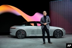 Kenichiro Yoshida, chairman, president and CEO of the Sony Group Corporation, stands in front of a newly unveiled electric vehicle prototype car Afeela, a joint venture between Sony and Honda, during a Sony news conference before the start of the CES tech show Wednesday, Jan. 4, 2023, in Las Vegas. (AP Photo/John Locher)