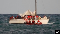 US Coast Guard members pull up alongside a sailboat carrying a large group of migrants off Virginia Key near Key Biscayne, Fla., on Jan. 12, 2023.