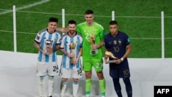 Argentina's Enzo Fernandez, Lionel Messi, Emiliano Martinez and France's Kylian Mbappeafter receiving the Young Player, Golden Glove, Golden Boot and Golden Ball awards respectively, during the Qatar 2022 World Cup trophy ceremony after the football final match between Argentina and France at Lusail Stadium in Lusail, north of Doha on December 18, 2022.