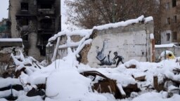 Sebuah karya seni yang dibuat oleh seniman jalanan Inggris Banksy terlihat di sebuah bangunan yang dihancurkan oleh tentara Rusia, di antara puing-puing yang tertutup salju di Borodyanka, wilayah Kyiv, Ukraina, Selasa, 6 Desember 2022. (AP/Efrem Lukatsky)