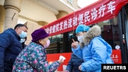 중국 장쑤성 후아이안시에서 보건요원이 25일 이동식 발열 치료소 앞에서 한 주민에게 설명하고 있다. (자료사진)
